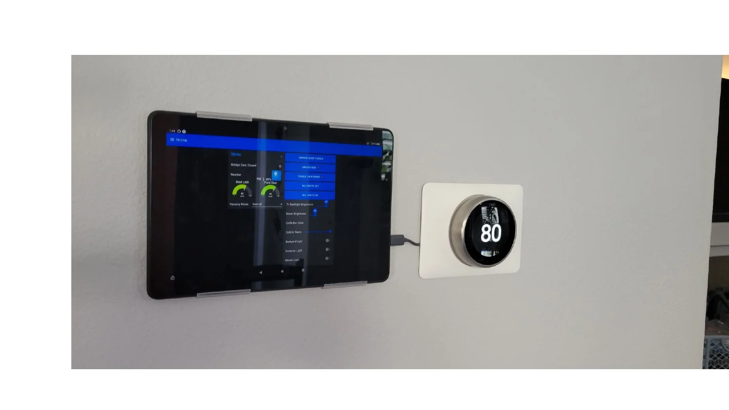 Wall-mounted tablet dashboard next to a Nest thermostat set to 80
